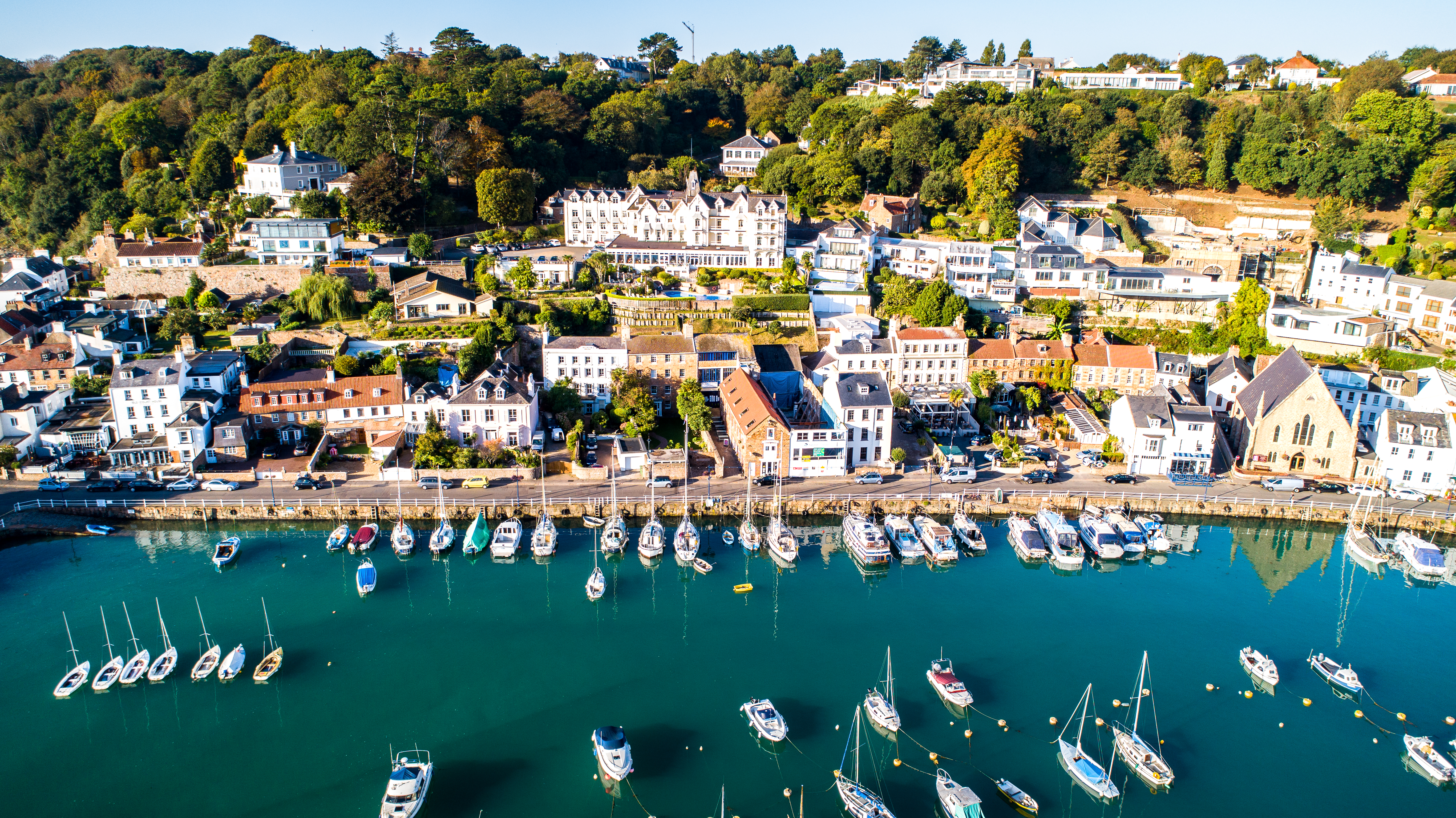 An aerial shot of the marina and the coastal road along St. Aubin's. Houses and restaurants can be seen in the background.